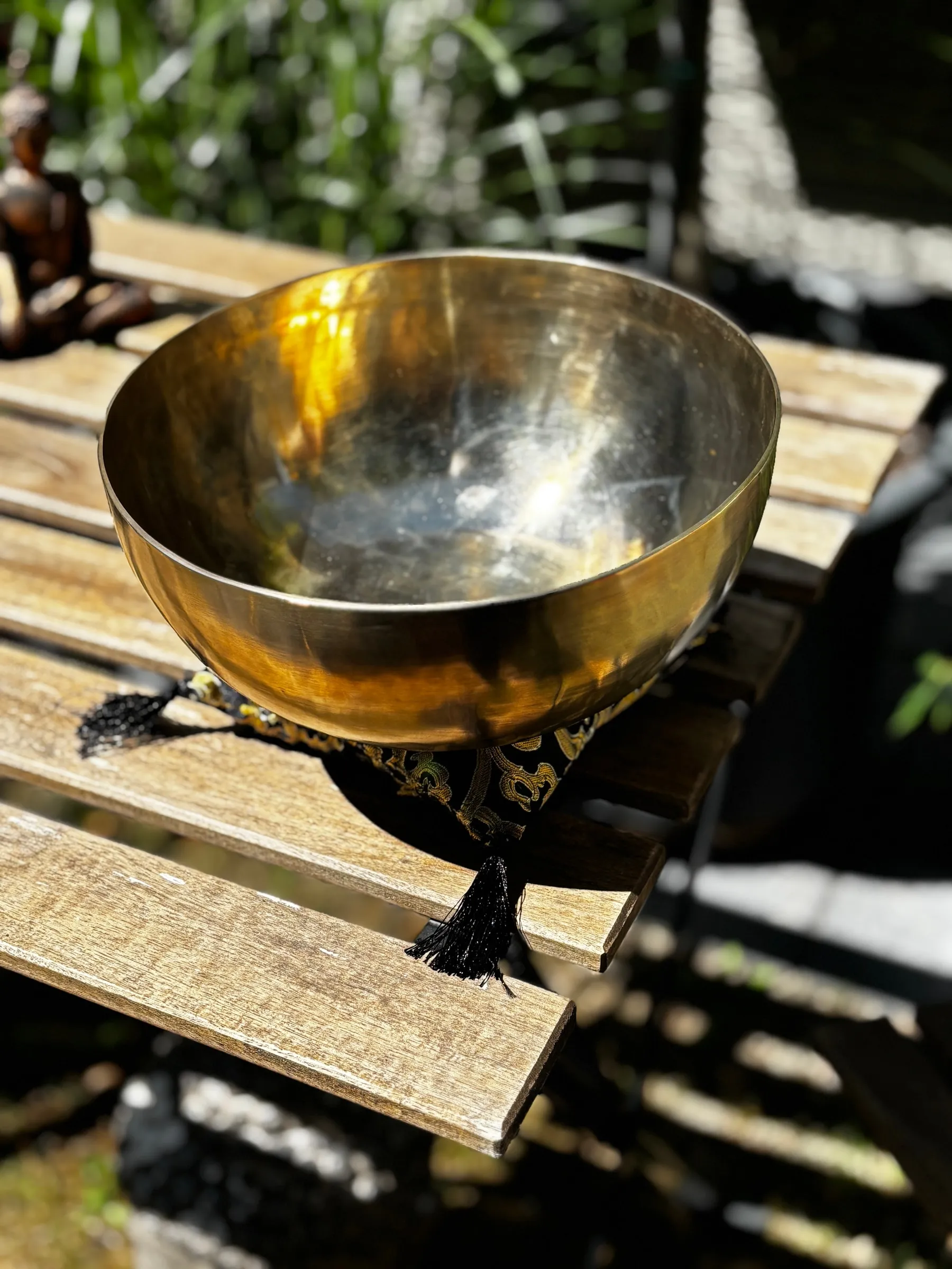 Goldene Klangschale auf einem Brokatkissen, warm beleuchtet vom Sonnenlicht