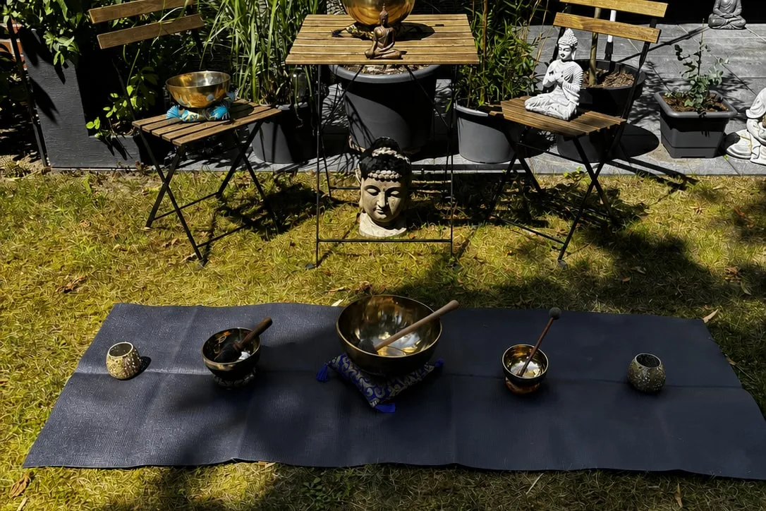 Eine Matte mit mehreren Klangschalen im Garten, vorbereitet für eine Klangreise